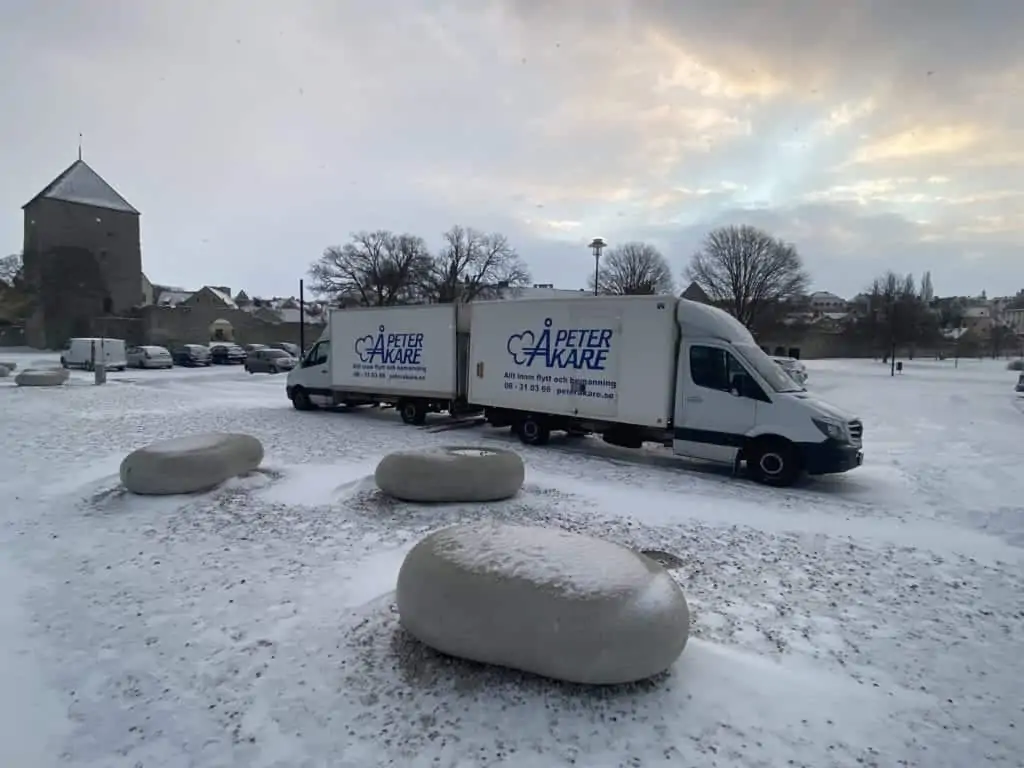 Två flyttbilar från Flyttfirma Peter Åkare AB uppställda utomhus med snövit bakgrund på Gotland
