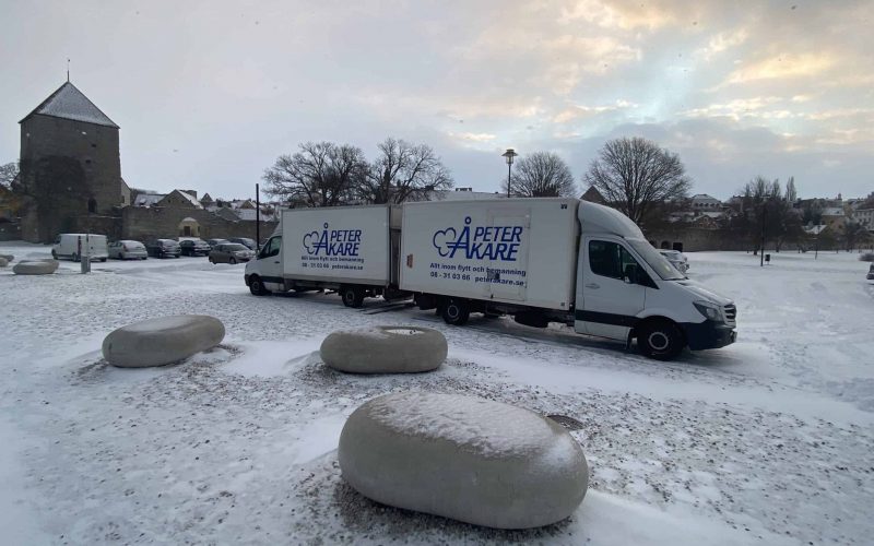 Två flyttbilar från Flyttfirma Peter Åkare AB uppställda utomhus med snövit bakgrund på Gotland