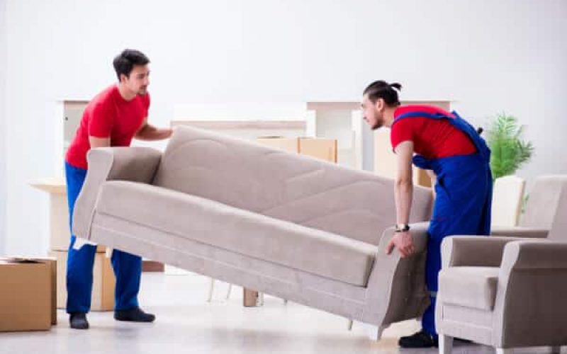 Två arbetare bär en soffa
